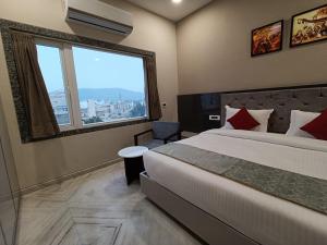 um quarto de hotel com uma cama e uma grande janela em Hotel Shri Anand Dham, Nathdwara - 125 Meters away from the temple em Nathdwara