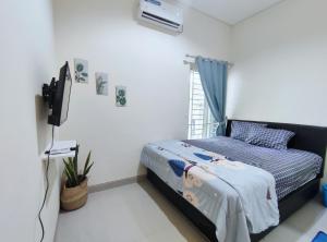 een slaapkamer met een bed en een televisie. bij Surabaya Homey near Juanda Airport Syariah in Sedati