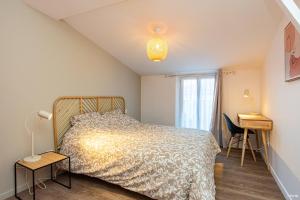 阿讓的住宿－LE DUPLEX - T6 COEUR DE ViLLE，一间卧室配有一张床、一张书桌和一个窗户。