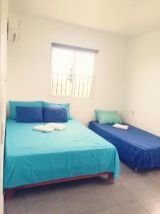 2 Betten in einem Zimmer mit blauer Bettwäsche und einem Fenster in der Unterkunft La CASA AZUL - Das blaue Haus - The blue house in Las Galeras