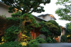 una casa con un árbol delante de ella en Marukyu Ryokan en Izu