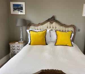 a bedroom with a bed with yellow pillows at The White House Hotel in Newquay