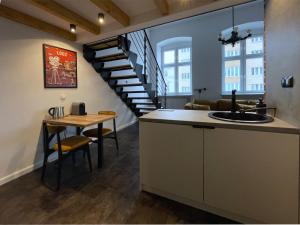 a kitchen with a staircase and a table with a sink at OFF Side Story Apartment in Łódź
