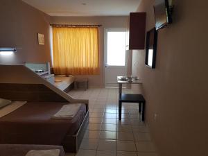 a small room with a bed and a table and a window at Asteraki ApartHotel in Gouvia