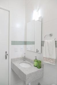 a white bathroom with a sink and a mirror at Apartamento Atalaia in Porto Alegre