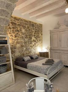une chambre avec un lit et un mur en pierre dans l'établissement LEMON SUITE Ortigia, à Syracuse