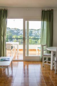 a living room with a table and chairs and a balcony at Apartamentos Encanto Del Mar in Cala Galdana