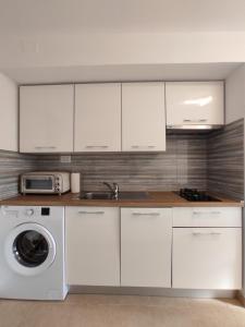 a kitchen with white cabinets and a washing machine at Apartman Studio Lu in Nerezine