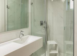 La salle de bains blanche est pourvue d'un lavabo et d'une douche. dans l'établissement Porto River Infante, à Porto