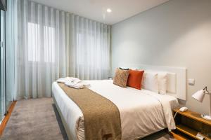 a bedroom with a large white bed with orange pillows at Porto River Infante in Porto