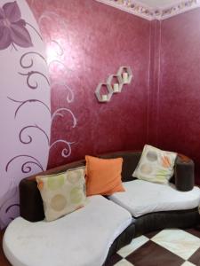 a room with two beds and a purple wall at App11- BELAL - Enjoy the privacy of staying in a quiet apartment with free Wi-Fi as your complete second home in the heart of Hurghada in Hurghada
