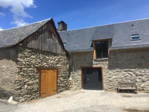 un antiguo edificio de piedra con dos puertas y un granero en Gîte de montagne Le Lustou, en Sailhan