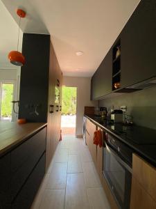 uma grande cozinha com armários pretos e piso em azulejo em Casa acogedora al pie de Montserrat em Collbató