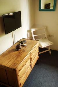 a room with a wooden dresser with a tv and a chair at The Blue Room in Mendoza