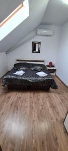 a bedroom with a bed and a wooden floor at Candy Pensiune&Restaurant in Dumbrava Roşie