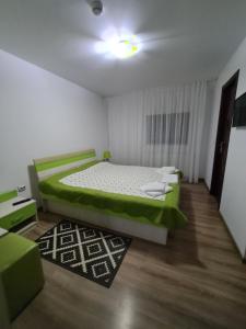 una piccola camera con un letto verde e un tappeto di Candy Pensiune&Restaurant a Dumbrava Roşie