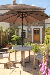 a table with an umbrella in front of a house at Sky Cottage in Fowey