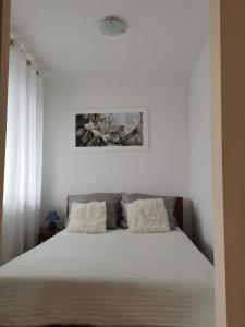 a white bedroom with a bed with white sheets at Apartament Reymonta przy morzu in Kołobrzeg