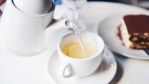 um bule de chá derramando leite numa chávena de café em Hotel Galaxy Inn em Calcutá