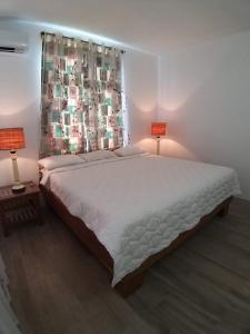 a bedroom with a large white bed with two lamps at Villa Trochetia in La Gaulette