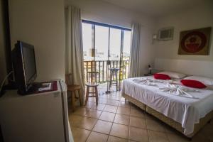 1 dormitorio con cama, TV y balcón en Pousada Al Mare, en Bombinhas