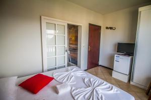 1 dormitorio con cama blanca y almohada roja en Pousada Al Mare, en Bombinhas