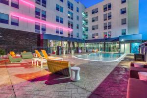 un patio del hotel con piscina, sillas y edificios en Aloft Dallas Arlington Entertainment District en Arlington