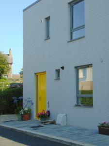 a yellow door on the side of a white house at Driftwood, Donaghadee in Donaghadee