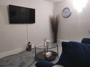 a living room with a table and a clock on the wall at Welcome to St Helena Dunoon, a traditional villa in Dunoon