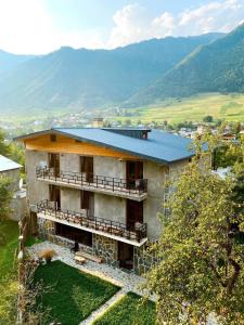- un bâtiment avec un balcon et des montagnes en arrière-plan dans l'établissement Hotel panorama svaneti, à Mestia