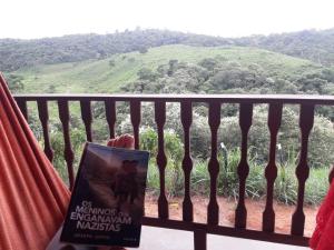 un libro sentado en un balcón con vistas a la montaña en Chalé com Vista Privilegiada en Pilões de Dentro