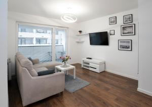 a living room with a couch and a tv at Apartament AQUAROOM Reda in Reda