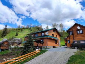 a large wooden house with a hill in the background at Sadyba Geredzhuka in Vorokhta