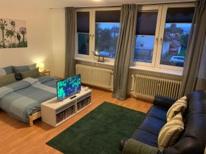 a living room with a bed and a tv and a couch at Haus am Stadtrand mit super Verbindung in die City in Kassel