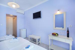 Habitación azul con cama, mesa y espejo en Eleani Hotel en Prinos