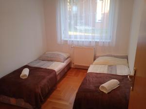 two beds in a small room with a window at Family apartment-családias hangulat in Győr