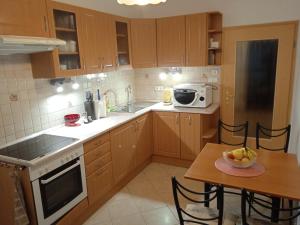 a kitchen with wooden cabinets and a table and a microwave at Family apartment-családias hangulat in Győr
