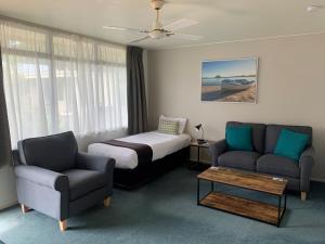 a hotel room with a bed and a couch and chairs at Academy Motor Inn in Tauranga