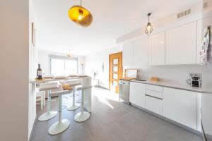 a white kitchen with white cabinets and a counter at MEDANO4YOU The Casa Celou Penthouse in La Tejita