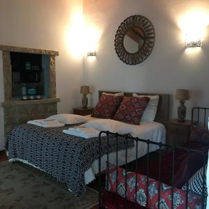 1 dormitorio con cama y espejo en la pared en Moradia rural de charme agradável e acolhedora, en Arrimal