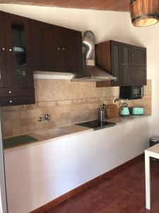 eine Küche mit braunen Schränken und einem Waschbecken in der Unterkunft Moradia rural de charme agradável e acolhedora in Arrimal