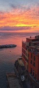 a sunset over the water with a building and the ocean at Pepita di Rio in Riomaggiore