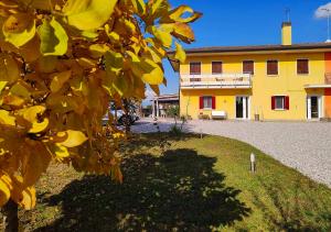 un bâtiment jaune avec un arbre devant lui dans l'établissement YARD 151, à Noventa di Piave
