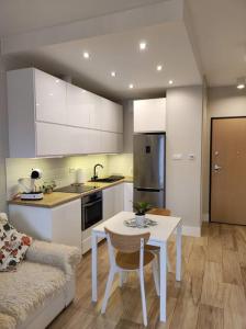 a kitchen with white cabinets and a table and a couch at Sweet Apartment vis-a-vis Medicover and Paley Institute in Warsaw