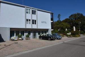 twee auto's geparkeerd voor een wit gebouw bij Hotel Markgraf in Bad Bellingen