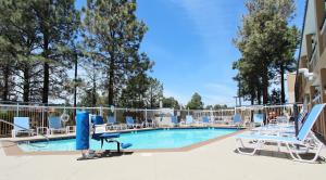 une piscine avec des chaises longues et un terrain de volley-ball dans l'établissement Baymont by Wyndham Flagstaff, à Flagstaff