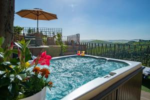 bañera de hidromasaje con sombrilla en el patio trasero en IL Castellano con jacuzzi e bellavista, en Castelfalfi