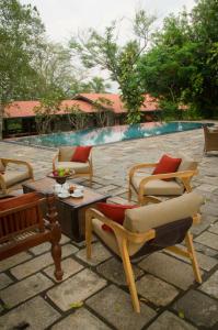 a patio with chairs and a table and a pool at Stone House, Kandy in Kandy