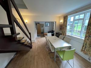 een woonkamer met een tafel en stoelen en een trap bij Garden House in Nailsworth