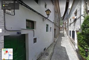 un callejón con una puerta verde en un edificio blanco en La Borda de Quevedo, en Biescas